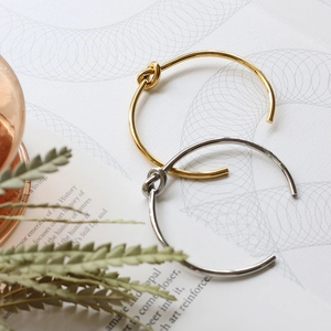Artistic display of minimalist gold and silver knot bangles on a magazine background