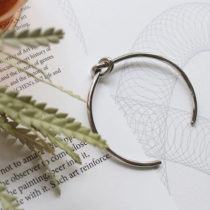 Detailed view of silver knot cuff bracelet on an artistic book page background