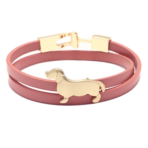 Détail d'un bracelet double tour en cuir rose avec breloque teckel dorée et boucle métal