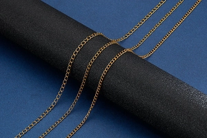 Detailed view of multiple gold flat link stainless steel chains on a black display stand