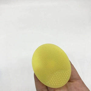 Close-up of yellow oval silicone cleansing brush with soft bristles and massage nubs