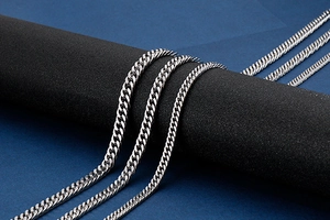 Macro view of three silver stainless steel Cuban link necklaces on a black display stand