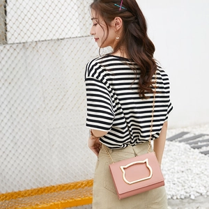 Chic pink crossbody bag with gold cat-head metal frame and chain strap on female model