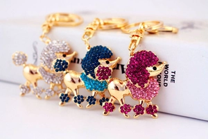 Detailed view of three crystal poodle keychains in gold, blue, and pink finishes