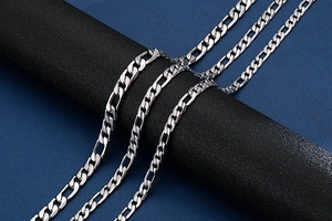 Detail of 9mm silver stainless steel Figaro link chains on a black cylindrical display