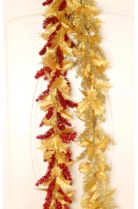 Close-up of artificial Christmas garland with gold leaves and red glitter berries on white door