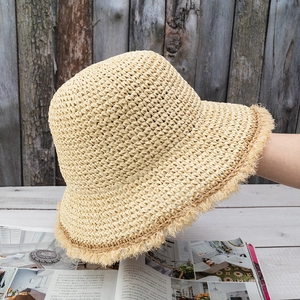 Detailed close-up of beige crochet straw bucket hat with vintage frayed brim details