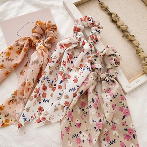 Detailed view of floral chiffon scrunchies with ribbons in cream, pink, and apricot