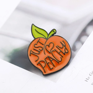 Detailed view of peach-shaped enamel pin with Just Peachy text on open book pages