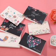 Detailed view of floral and bird print thank you greeting cards on a pink background