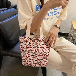 Dettaglio della borsa a mano plissettata bianca con stampa floreale e manici in tela