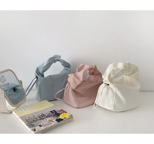 Détail d'un petit sac à main avec poignée plissée en bleu, rose et blanc cassé