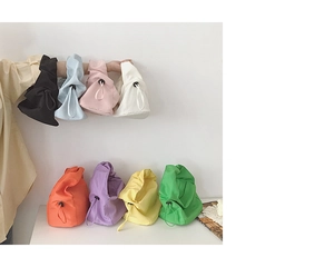 Détail de sacs en toile à cordon colorés en huit tons disposés sur une table blanche