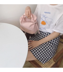 Sac à main minimaliste en tissu rose tenu par un mannequin dans un décor lumineux