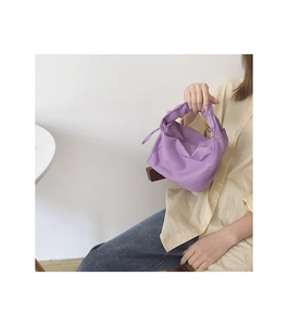 Gros plan d'un sac baguette lilas avec poignée nouée et plis de tissu drapés