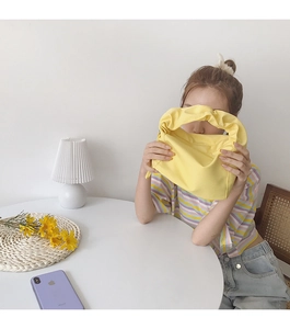 Sac baguette minimaliste en toile jaune vif tenu par un mannequin dans une scène épurée