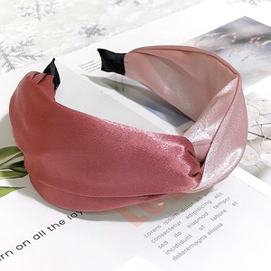 Close-up of pink satin wide headband with stylish knot detail on fashion magazine background