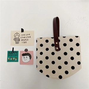 Close-up of French retro polka dot canvas bag with premium brown leather handle detail