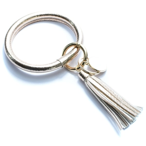 Detailed close-up of champagne gold PU leather O-ring keychain with fringe tassel and metal tag