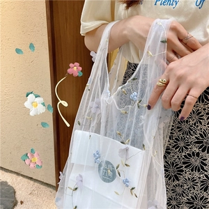 Detailed close-up of white mesh handbag with 3D colorful floral embroidery patterns
