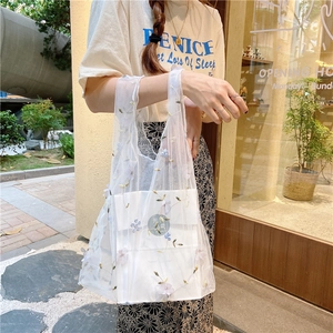 Detailed close-up of intricate 3D floral embroidery on a white mesh tote bag