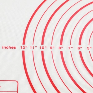 Detail of red circular inch markings on a white silicone baking mat with texture