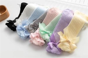 Detail of multi-color mesh baby socks featuring large satin bows and breathable knit