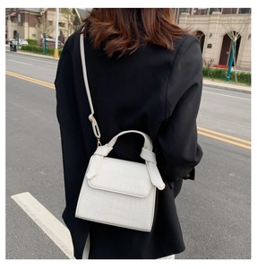 Rear view of a model wearing the white crocodile pattern square handbag with a gold chain strap