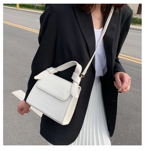 Detailed view of white crocodile pattern crossbody bag with a knotted top handle design