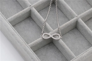 Silver infinity bracelet with white zircon stones in a gray velvet jewelry box display