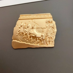 Detailed close-up of a golden Baroque Egyptian chariot relief brooch on dark background