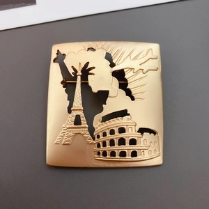 Matte gold baroque brooch featuring world landmarks in a hollowed square metal design