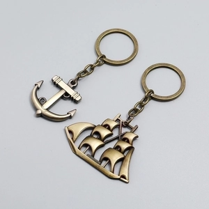 Vintage bronze sailing boat and anchor keychains in retro nautical theme style
