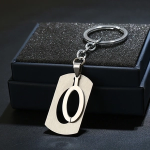 Close-up of stainless steel letter O keychain pendant on dark blue gift box