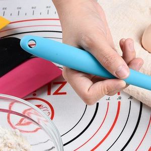 Large light blue silicone spatula for baking held over a professional pastry mat