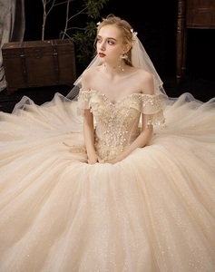 Close-up of champagne off-shoulder wedding dress with sequined lace and large luxury train