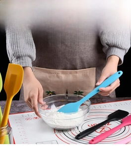 Blue silicone spatula mixing batter in glass bowl during kitchen baking process