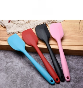 Set of four colorful silicone spatulas in blue red black and pink on a wooden board