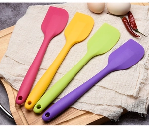 Set of four colorful silicone spatulas on a wooden board with rustic kitchen accents