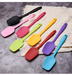Set of seven colorful silicone spatulas arranged on linen cloth over a marble surface