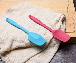 Close-up of blue and rose red food-grade silicone spatulas on a rustic wooden board