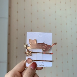 Detailed close-up of rose gold cat, star and planet hair clip set in hand display