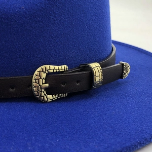 Close-up of cobalt blue felt hat featuring black faux leather band with gold metal buckle