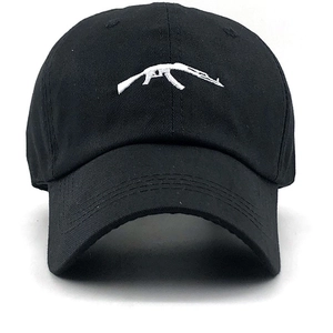 Close-up of a black cotton baseball cap featuring detailed white AK-47 rifle embroidery