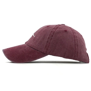 Detail of vintage burgundy washed cotton baseball cap with white side logo embroidery