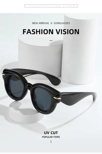 Close-up of black oversized round sunglasses with golden curved metal hinges and UV protection