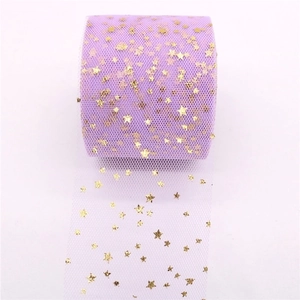 Close-up of purple tulle fabric roll featuring shiny gold star patterns for DIY crafts