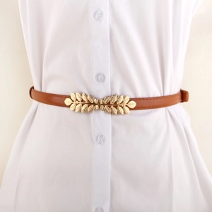 Brown slim leather belt with golden leaf buckle on a white dress for women