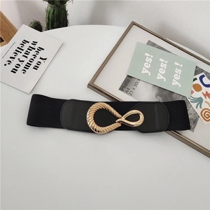 Elastic black waist belt with interlocking gold oval buckle on a minimalist white surface