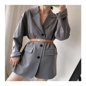 Detailed view of a brown leaf buckle belt cinched over a grey blazer for a stylish look